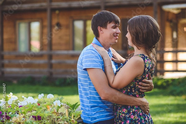 Fototapeta Romantic young couple hugging each other on the background of the hotel in a rustic style.
