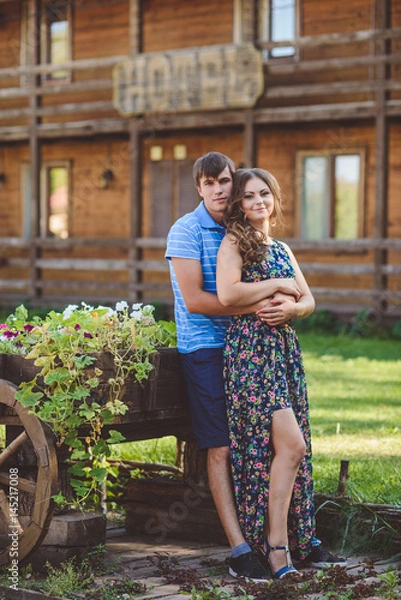 Fototapeta Romantic young couple hugging each other on the background of the hotel in a rustic style.