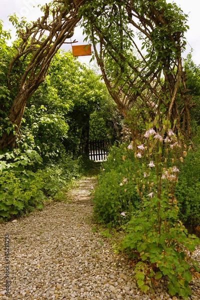 Obraz Bewachsener Torbogen mit Weg in einem Garten