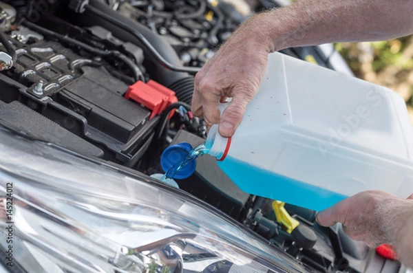 Obraz Hands of mechanic pouring washer in a car