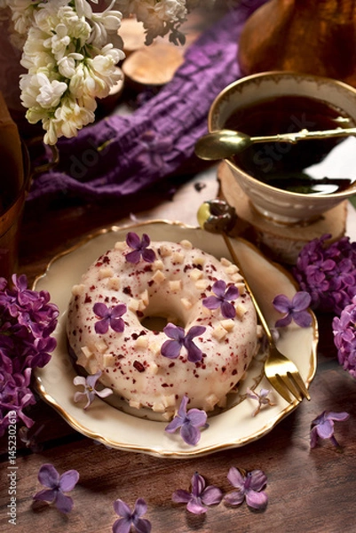 Obraz Delicious donut with white chocolate glaze and black berry filling with purple lilac decoration