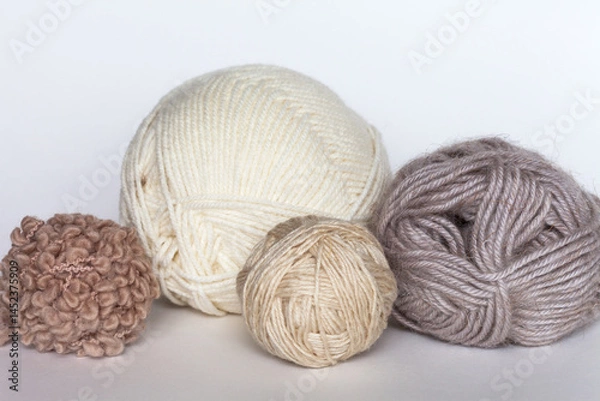 Fototapeta Different types of wool yarn for hand knitting in beige colors on white table. Merino wool, wool-acrylic blend, boucle yarn in balls and skeins. Knitting as hobby. DIY concept. Close-up. Front view