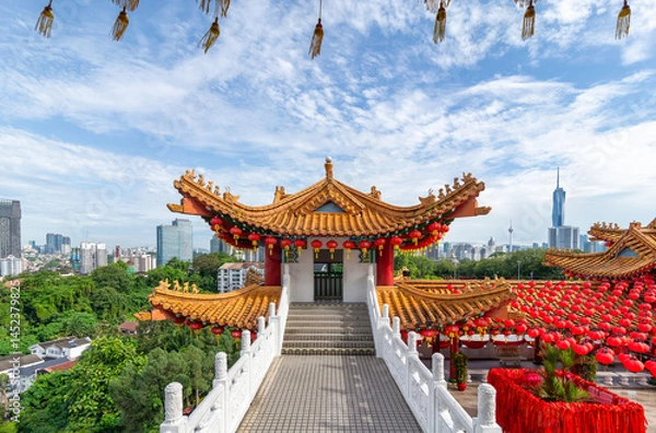 Fototapeta The stunning architecture of Thean Hou Temple, framed by lush greenery, under a vibrant sky. The site is adorned with red lanterns, creating a festive atmosphere