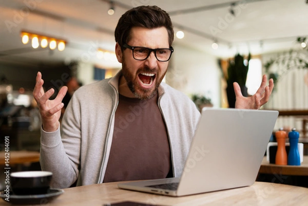 Fototapeta Angry businessman yelling at laptop in cafe, having problem with computer