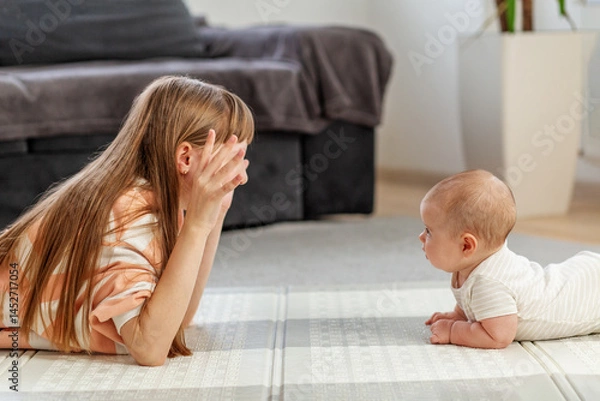 Fototapeta Siblings enjoy playful interaction on soft mat in cozy living room during afternoon.