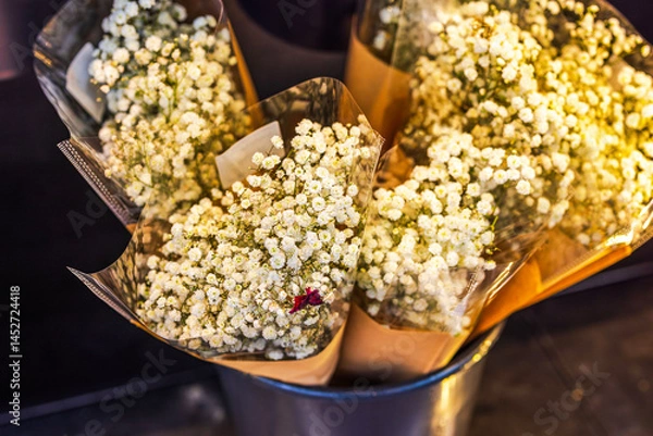 Fototapeta Bouquets of fresh white baby's breath flowers wrapped in paper and plastic in metal flower bucket display. Sweden.