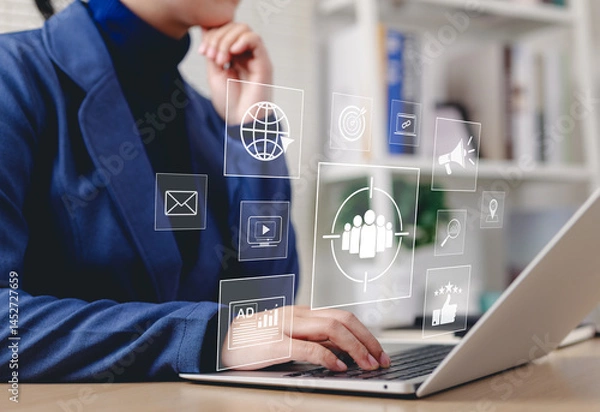 Fototapeta Digital Marketing Strategy and Target Audience Concept. Businessperson working on laptop with digital icons representing email, analytics, audience targeting, SEO, video, campaign, and online ads.