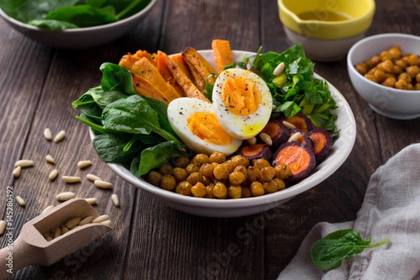 Fototapeta Lunch bowl with sweet potatoes, chickpeas, spinach, carrots and boiled egg