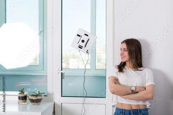 Obraz Woman cleaning windows with robotic cleaner