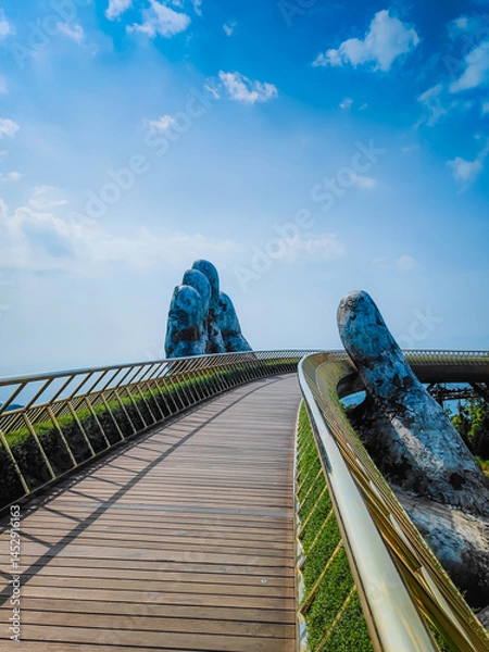 Fototapeta Empty Golden Bridge in Ba Na hills, Da Nang, Vietnam on a sunny day. Lifted by two giant concrete hands. Iconic world famous bridge in the mountains