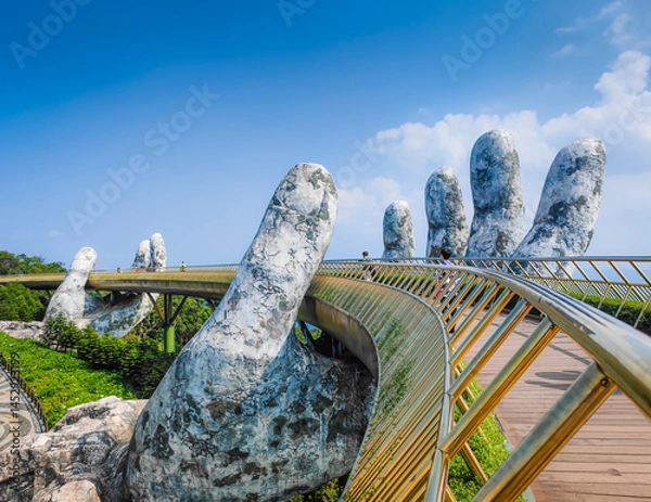 Obraz Golden Bridge in Ba Na hills, Da Nang, Vietnam on a sunny day. Lifted by two giant concrete hands. Iconic world famous bridge in the mountains