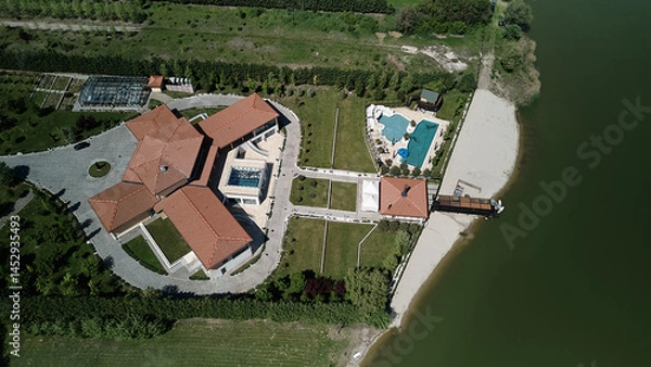 Obraz Aerial view of a countryside resort on Pavlovac Lake, Serbia. Villas, pools, and a private beach surrounded by fields and gentle hills on a clear spring day.