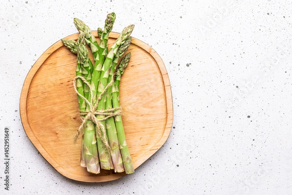 Obraz Raw organic asparagus on decorative wooden tray on light marble background top view, copy space for your design.