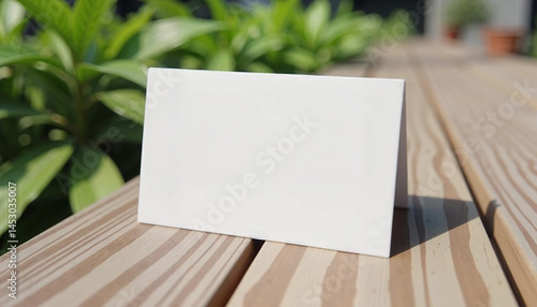 Fototapeta Blank folded card on wooden bench in garden setting

