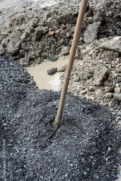 Fototapeta Shovel in gravel pile at construction site
Close-up of a shovel stuck into a mound of dark gravel, surrounded by crushed rock and soil at a roadwork location.
