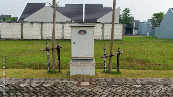 Fototapeta Electrical Utility Box in Grass Field Near Residential Area in wet pavement