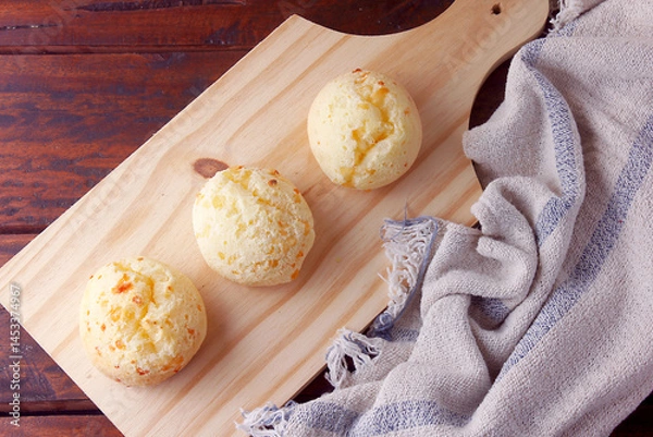 Fototapeta homemade cheese bread, traditional Brazilian snack, in the cutting table on a rustic kitchen table