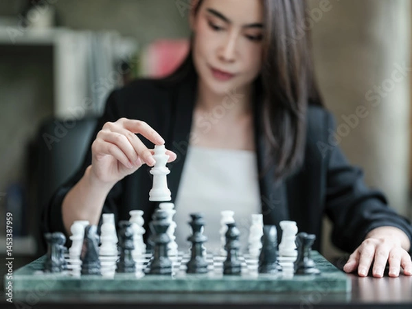 Fototapeta Asian businesswoman playing chess to plan business and market probability by using chess in work. Leadership concept.