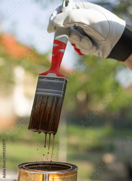 Obraz Close-up of a dipping brush into a bucket full of brown paint.