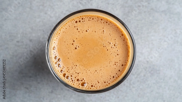 Fototapeta Rich Vietnamese coffee with creamy foam in glass, showcasing its inviting texture and color