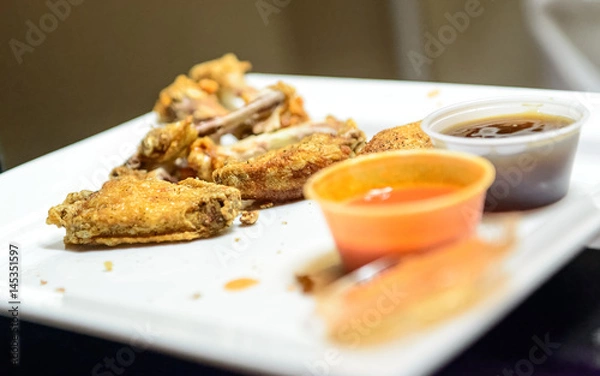 Fototapeta Partially eaten plate of chicken wings with sauces