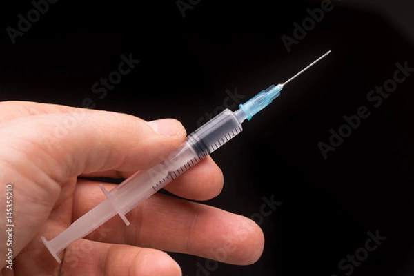 Fototapeta Hand holding a syringe