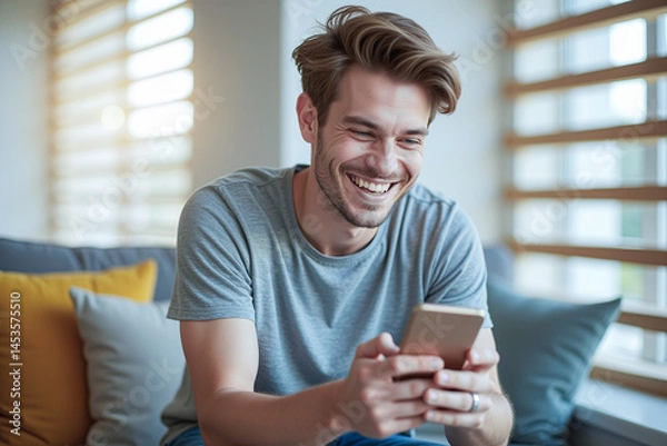 Fototapeta Happy man guy using smartphone at Home, smile and hold phone on he hand with internet technology use of shopping, search, chat, message at inddor living room with beautiful natural light
