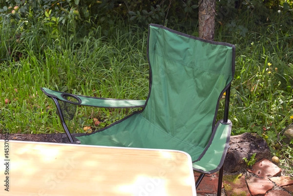 Fototapeta Set of folding furniture for camping, table and chair, summer nature of wild meadow