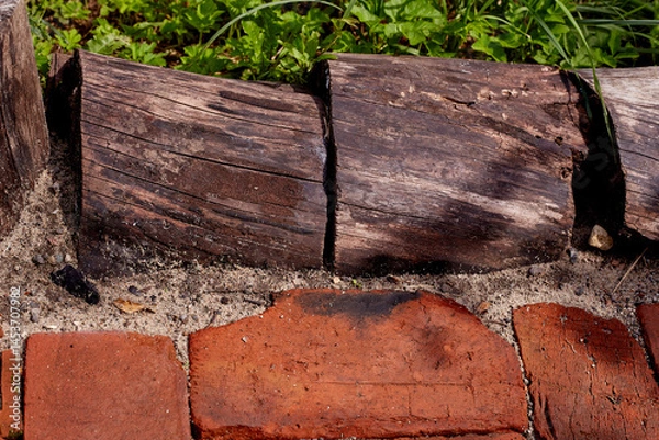 Fototapeta The texture is red old brick, tree stumps and green grass. rustic style. the patio. recreation area.