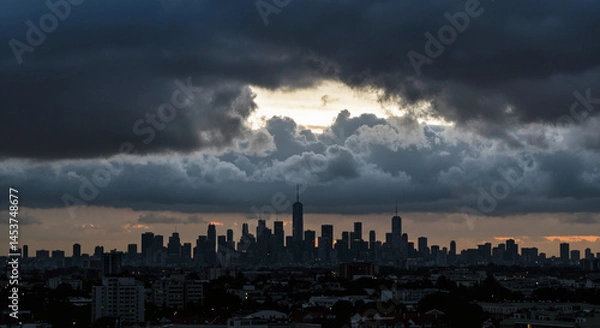 Fototapeta City skyline amid dark clouds during blackout in urban areas  