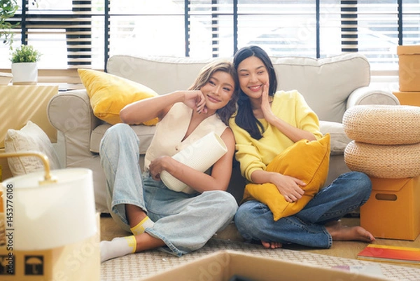 Fototapeta Young women and friend help moving home while packing boxes together and happy in new home.  Asia women investment real estate for living with family.  Investment and Family Concept