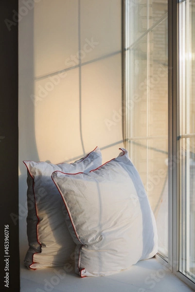 Obraz Two soft, cozy pillows are comfortably resting on a window sill, positioned directly in front of a beautiful, large window