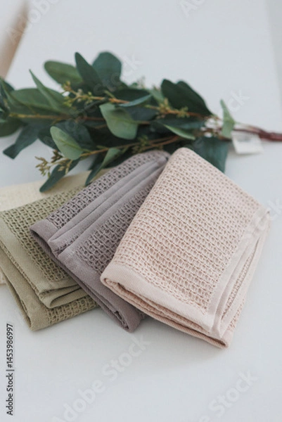 Obraz On a table, there are three towels neatly stacked one on top of the other, creating a tidy and organized appearance