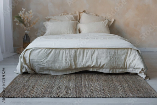Obraz In a cozy bedroom, there is a comfortable bed adorned with crisp white sheets and fluffy pillows placed atop a stylish rug
