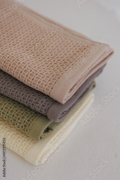 Fototapeta Three towels are carefully stacked, one on top of the other, resting neatly on a table surface for easy access and organization