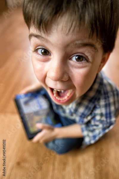 Fototapeta The boy with the tablet was very surprised at what he saw. Strong surprise. Optical distortion of the picture.