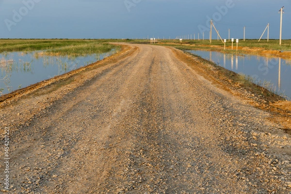 Fototapeta Gravel road through flooded fields in Kazakhstan landscape