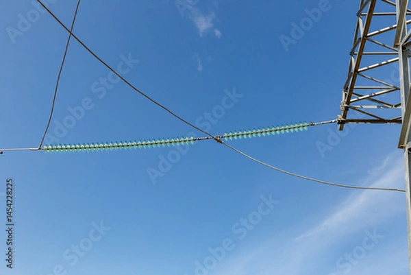 Fototapeta Insulators on power transmission line under clear blue sky