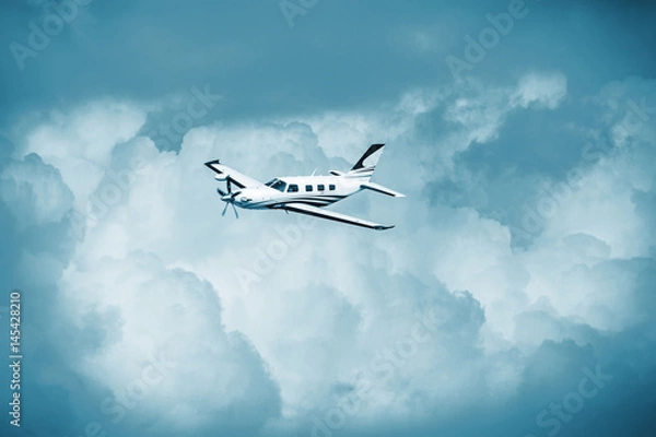 Fototapeta Single turboprop aircraft.. Small private plane flying in blue clouds.