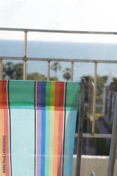 Fototapeta Colorful striped fabric hanging to dry in sunlight near a window. Bright textile drying outdoors.