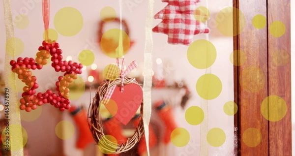 Fototapeta Image of yellow dots moving over window with christmas decoration