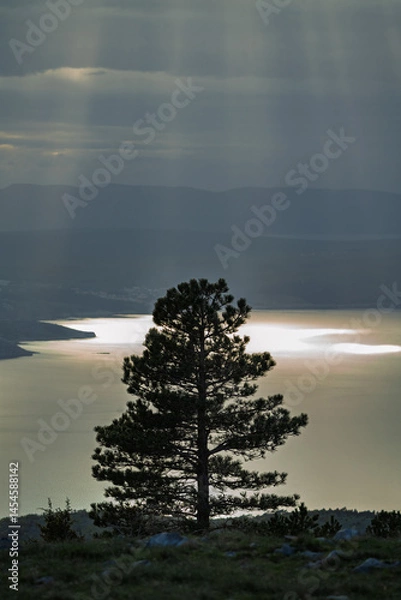 Fototapeta Sunlight falls through the clouds and is reflected in the waters of the Adriatic.