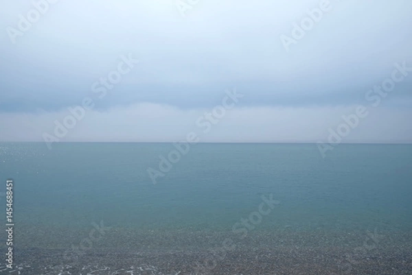 Fototapeta Flat mediterranean sea surface till horizon under cloudy foggy sky in overcast day