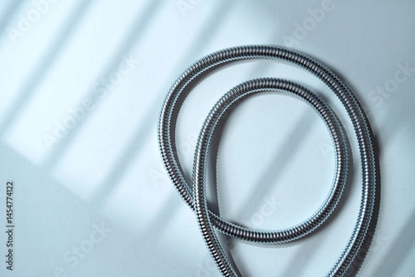 Obraz Stainless steel shower hose elegantly placed on soft surface.