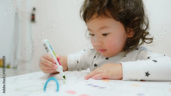 Obraz Cute child focused on drawing with markers, showcasing creativity education and concentration in a cozy home environment.