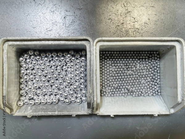 Obraz top view of two gray plastic boxes filled with steel balls of various diameters, bearing balls or calibrated balls on an assembly line