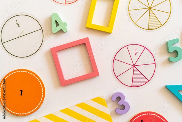 Fototapeta Educational learning tools arranged on a surface with colorful shapes, numbers, and fraction circles for interactive math activities with children. education,  back to school