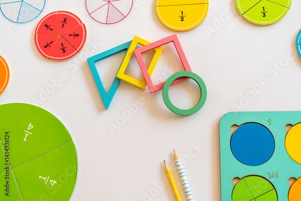 Fototapeta Colorful educational math manipulatives arranged on a table with circular fraction pieces and geometric shapes indicating a learning environment for children