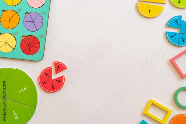 Fototapeta Colorful educational manipulatives for teaching fractions on a white surface in a classroom setting during daytime. education,  back to school