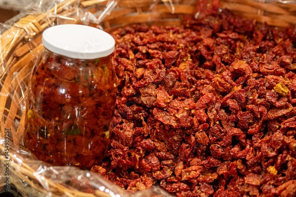 Fototapeta Sun-dried red cherry tomatoes in a wicker basket with price in a street food market in Bari, close up